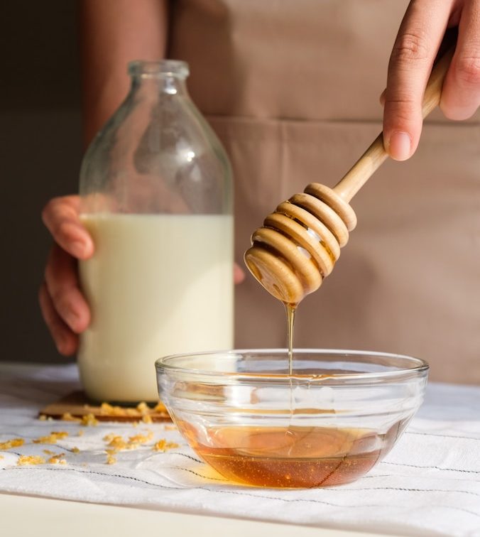 person holding clear glass jar with white liquid